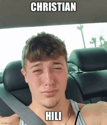 a young man is sitting in a car with a funny caption that says christian hili