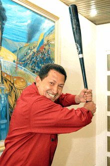 a man in a red shirt is holding a baseball bat and smiling in front of a painting