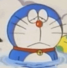 doraemon is sitting in the water with his eyes closed and a red nose .