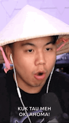a man wearing a conical hat is talking into a microphone while wearing headphones .