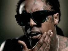 a man wearing sunglasses has a tattoo on his face