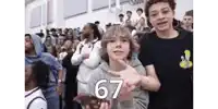 a group of young people are standing in a gym and one of them has the number 67 on his shirt