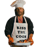 a man wearing an apron that says kiss the cook holds a tray of food