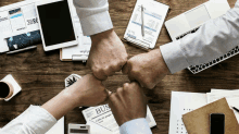 a group of people giving each other a fist bump in front of a bus newspaper