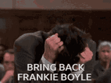 a man in a suit holds his head in his hands with the words bring back frankie boyle below him