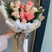 a person is holding a bouquet of pink roses wrapped in white paper