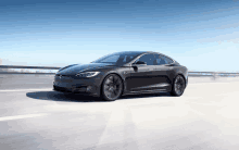 a black tesla model s is driving down a highway