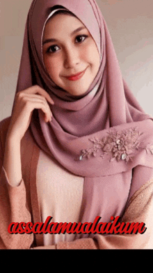 a woman wearing a pink hijab with the word assalamualaikum written in red