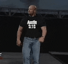 a man wearing a black shirt that says `` austin 3:10 '' is walking on a stage .