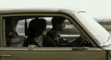 a man driving a car with two women sitting in the back seat