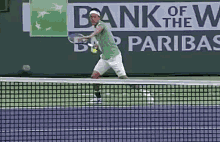 a tennis player is swinging a tennis racquet on a court with a bank of the west banner behind him