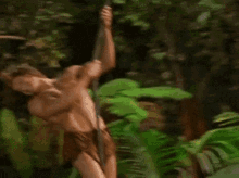 a naked man with long hair is leaning against a tree trunk .