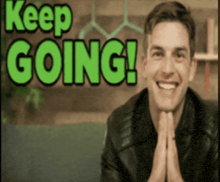 a man is smiling in front of the words keep going