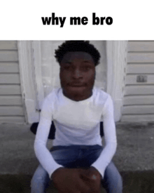 a man in a white shirt is sitting in front of a door with the words why me bro written on the bottom .