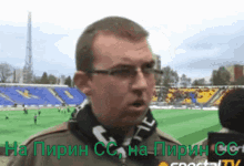 a man wearing glasses stands in front of a stadium with the words na pirin cc na pirin cc written in green