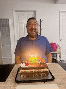 a man is sitting in front of a birthday cake with candles .