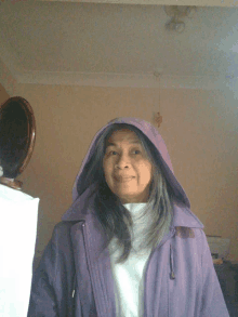 an older woman wearing a purple jacket with a hood