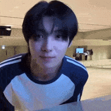 a young man in a blue and white shirt is standing in front of a mirror .