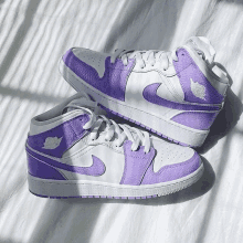 a pair of purple and white nike shoes on a white surface