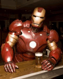 a man in an iron man suit is sitting at a bar with a glass of beer