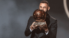 a man in a suit is holding a trophy that says ' soccer ' on it