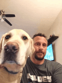 a man and his dog are posing for a picture and the dog is wearing a shirt that says oldes