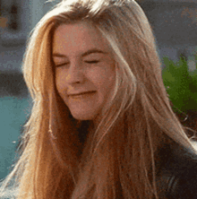 a woman with long blonde hair is smiling and looking down