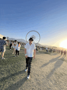 a man stands in front of a large ferris wheel