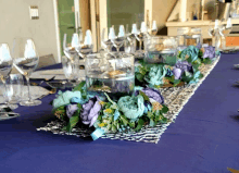 a table with purple and blue flowers and wine glasses