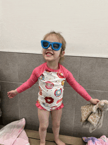 a little girl wearing sunglasses and a swimsuit with doughnuts on it