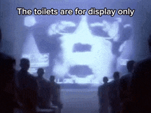 a group of people watching a display of a face with the words " the toilets are for display only "