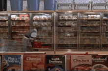 a woman is standing in front of a refrigerated section of a grocery store that sells pies and pastries and light desserts