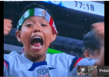 a young boy wearing a usa jersey is screaming with his mouth wide open