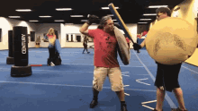 a man wearing a red shirt that says ' emperor ' on it stands in front of a century punching bag