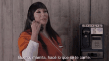 a woman talking on a payphone with bueno mamita