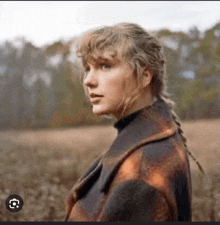 taylor swift is standing in a field wearing a plaid coat and a braid .