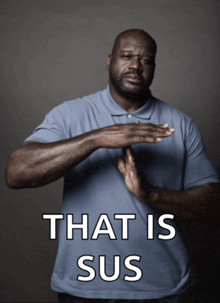 a man in a blue shirt is making a stop sign with the words that is sus behind him