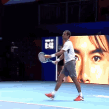 a man is holding a tennis racquet on a tennis court with a sign that says 6:48 in the background