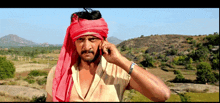 a man wearing a red turban is talking on his cell phone