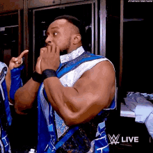 a man in a blue and white outfit is standing in a locker room with his hands to his mouth .