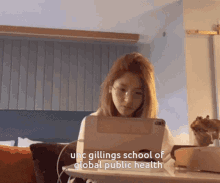 a woman sits at a desk with a tablet and the words " unc gillings school of global public health " above her