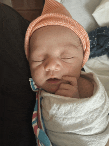 a newborn baby wrapped in a blanket and wearing a pink hat