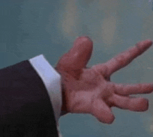 a close up of a man 's hand in a suit reaching out towards something .