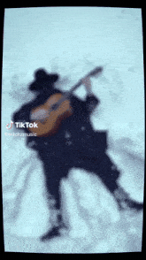 a blurred image of a man playing a guitar with tiktok written on the bottom right