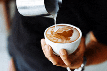 a person pours milk into a cup of coffee