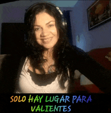 a woman wearing headphones is smiling with the words solo hay lugar para valientes below her