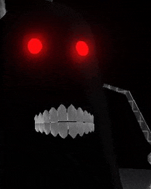 a black robot with red eyes and white teeth is glowing in the dark .