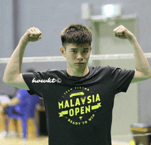 a young man flexes his muscles wearing a malaysia open shirt