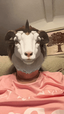 a person wearing a goat mask and a pink shirt with the letter g on it