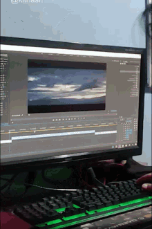 a computer monitor displays a picture of a cloudy sky and a keyboard